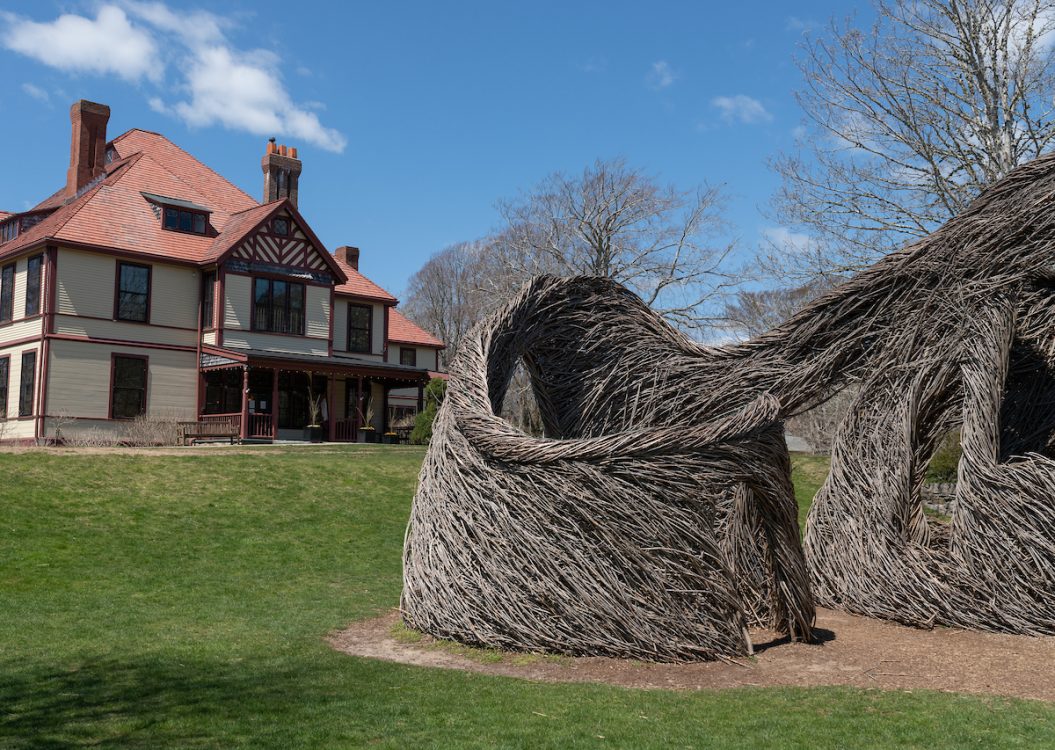 Exterior of Highfield Hall with Patrick Dougherty's stickwork sculpture in front.